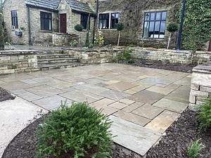 stone patio area with stone raised beds to compliment the stone walled home