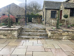 stone patio and steps with raised stone walled beds with planting