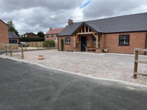 Newly installed block paving driveway for a red-brick house in Nottinghamshire, featuring a low timber fence.