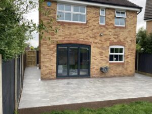 Professional landscape gardeners installed a new light gray paving stone patio outside bi-fold doors.